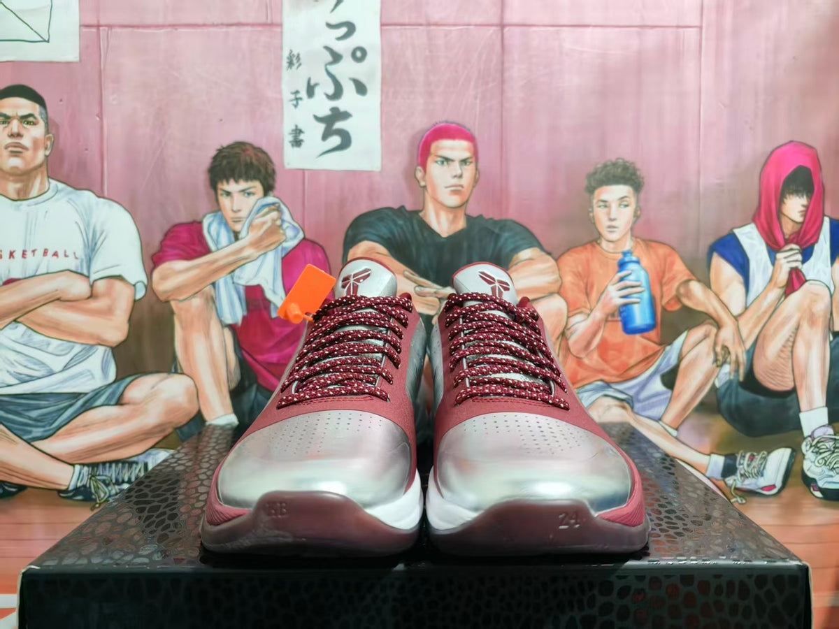 Front view of silver and white Nike basketball sneakers with burgundy laces and accents, photographed against an illustrated basketball backdrop.