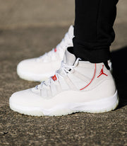 Outdoor side view of the white high-top sneaker with red accents and translucent outsole.