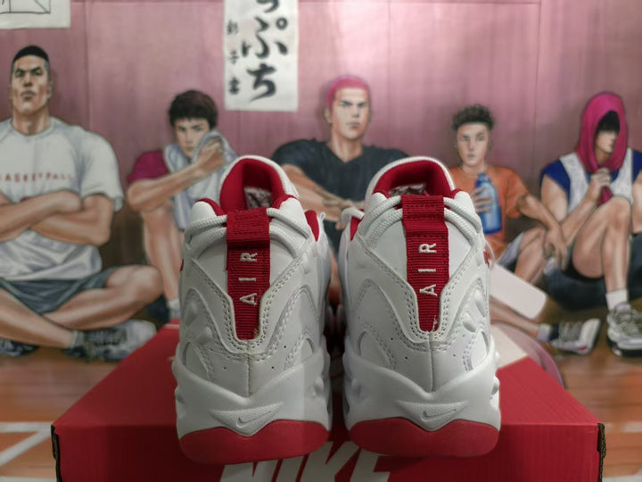 Rear view of white Nike sneakers with red heel accents and red branding details, displayed on a red Nike shoebox.