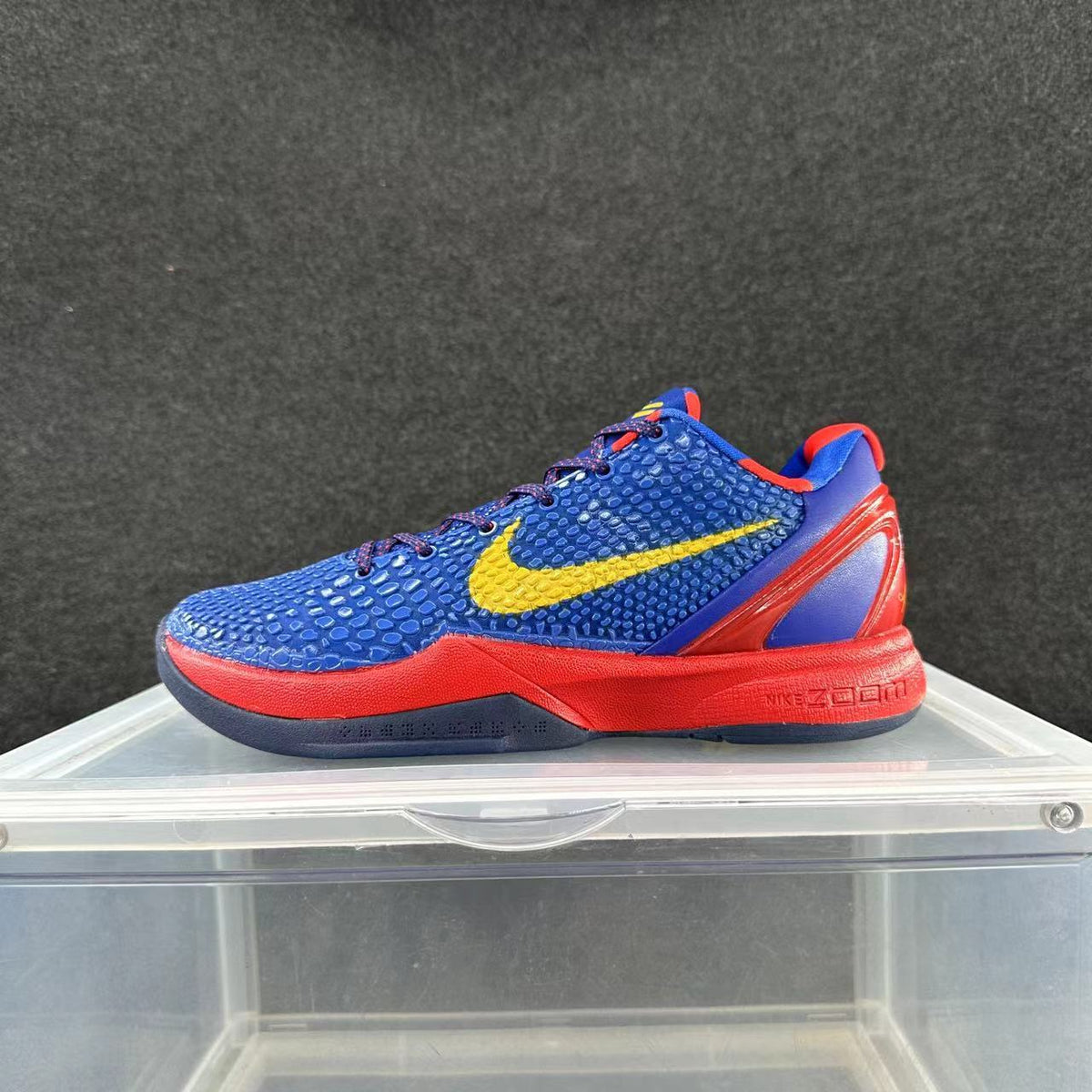 Side view of a blue Nike basketball shoe with a yellow Swoosh, red accents, and a low-cut profile.
