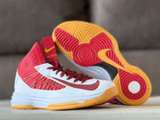Basketball shoes displayed with one shoe showing the red and gum-colored patterned outsole.