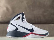 Side view of a white high-top Nike basketball shoe with black and red accents