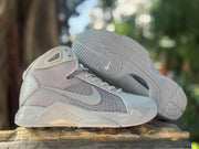Nike high-top sneakers shown from the side with one outsole facing upward, revealing patterned traction sections.