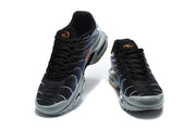Front view of black and grey Nike Air Max Plus sneakers with orange details