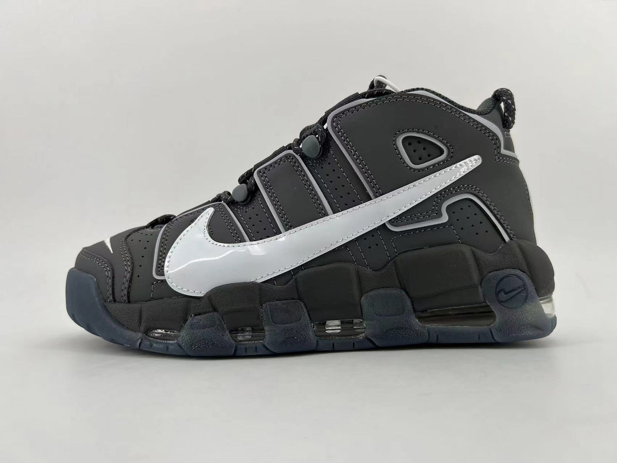 Side view of a black and dark gray Nike low-top sneaker with a large silver Swoosh and chunky segmented sole