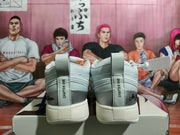 Rear view of white and grey low-top sneakers showing heel tabs and decorative text.