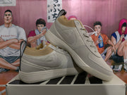 Angled view of paired beige low-top sneakers showing the side marks, pull tabs, tonal construction, and rubber outsoles.