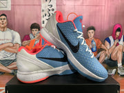 Angled view of paired blue, white, and orange Nike Zoom basketball sneakers displayed on a black box.