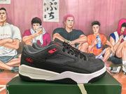 Side profile of a black and grey Jordan sneaker showing textured side panels, red branding and a layered sole.