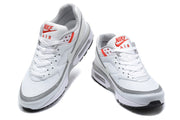 Front view of white Nike Air Max sneakers with red tongue branding