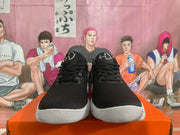 Front view of black Nike sneakers with silver tongue details and white ridged soles.