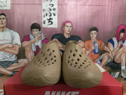 Front view of khaki Nike sneakers showing the perforated upper, rounded toe, and textured sole.