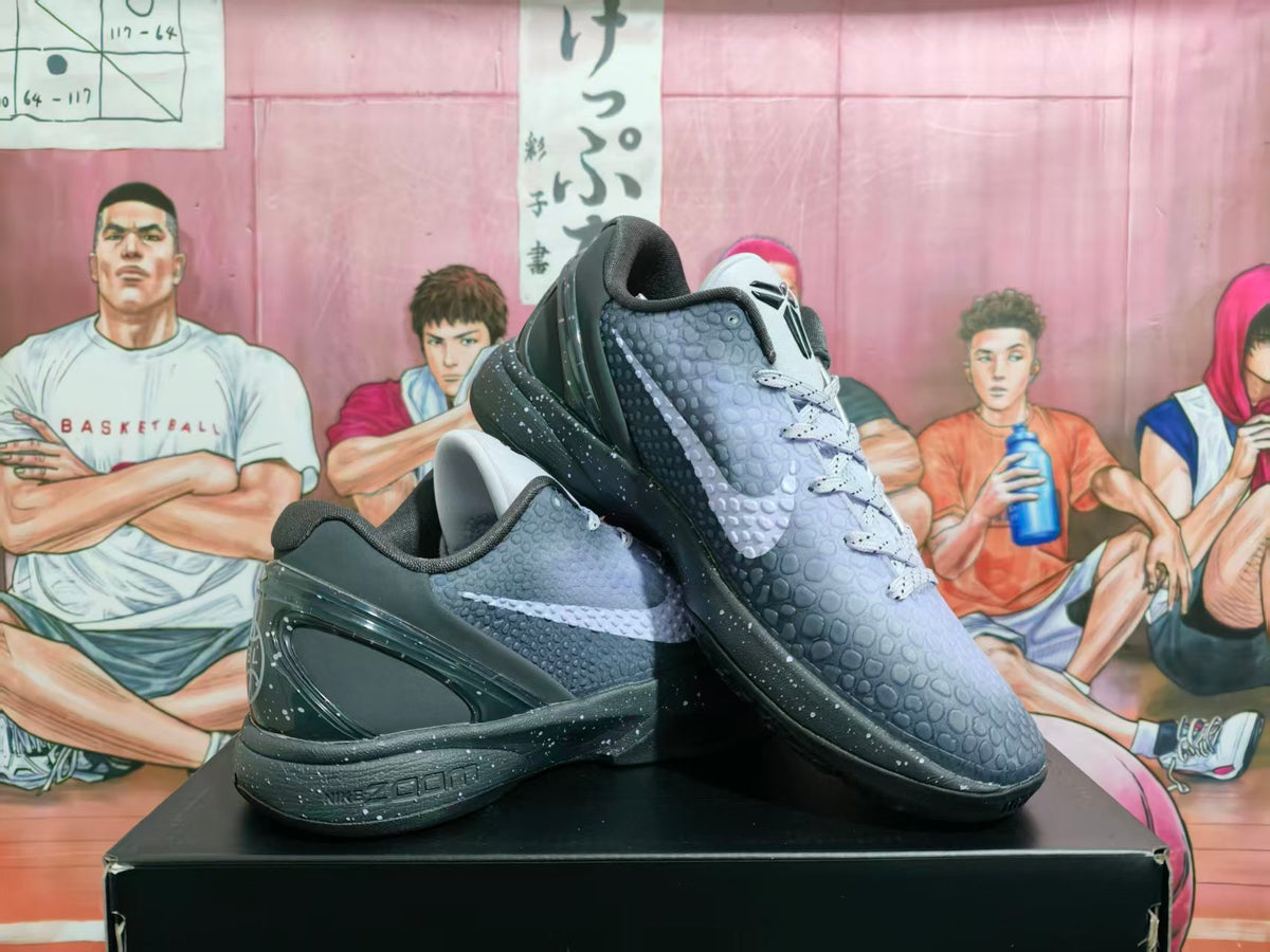 Pair of black and gray Nike EYBL basketball sneakers displayed on a black box, showing the textured upper and side Swoosh.