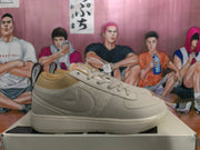Side view of a beige sneaker showing the layered upper, Swoosh-style side mark, tan collar lining, and textured outsole.