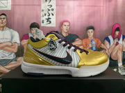 Side view of a gold, white, and navy Nike basketball shoe with striped panels and Kobe signature details
