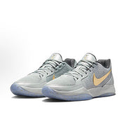 White and light gray Nike basketball sneakers with a gold Swoosh and pale blue outsole.