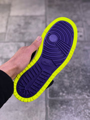 Close view of the sneaker outsole showing a purple tread pattern surrounded by a bright volt rubber edge.