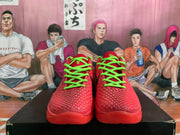 Front view of red Nike basketball sneakers with bright green laces, textured uppers, and red outsoles.