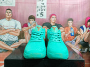 Front view showing the turquoise textured uppers, matching laces, and bronze Kobe-style tongue logos.