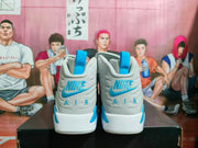 Rear view of gray and blue high-top sneakers showing blue heel branding, AIR lettering, and blue pull tabs on a black box.