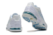 Rear and outsole views of white and blue Nike Air Max Plus sneakers.