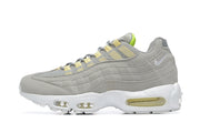 Side profile of a gray Nike Air Max 95 sneaker with layered panels, pale yellow accents, and a white sole.