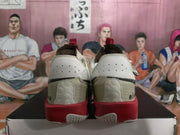 Rear view of white basketball sneakers with red midsoles, perforated heel panels, and black detailing.