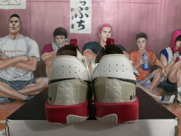 Rear view of white basketball sneakers with red midsoles, perforated heel panels, and black detailing.
