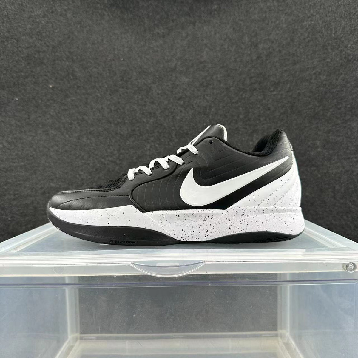 Side view of a black and white Nike low-top sneaker with white laces, a white Swoosh, speckled white midsole, and black outsole.