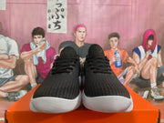 Front view of a pair of black lace-up sneakers with white soles.