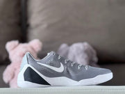 Side view of a grey and white low-top Kobe 9 shoe with dark heel accents.