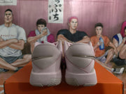 Rear view showing the padded heel sections and textured outsole pattern of the grey and pink sneakers.