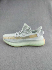 Side profile showing the knit upper, beige side stripe, heel pull tab, and ribbed sole.