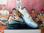 Angled view of white basketball shoes with blue soles and contrasting black and yellow details.