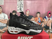Side view of a black Nike sneaker with mesh panels, oversized lettering, and white sole accents.