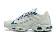 Side profile of a white Nike Air Max Tn sneaker with teal accents and a speckled sole.