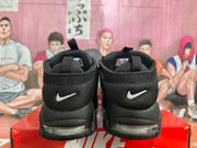 Rear view of black Nike sneakers showing heel branding, padded collars, pull tabs, and visible sole cushioning.