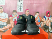 Front view of the black Nike basketball sneakers with gold tongue branding, black laces, and white midsole accents.