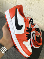 Angled side view highlighting the white toe panel, orange overlays, black laces and black side logo.