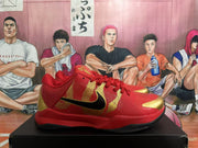 Side view of red basketball shoe with gold detailing and black Swoosh