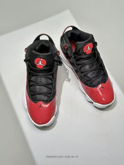 Top-down view showing black laces, padded tongues, red tongue emblems, and red toe panels.