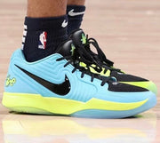 Black, light blue, and neon yellow Nike basketball shoe shown on a basketball court.