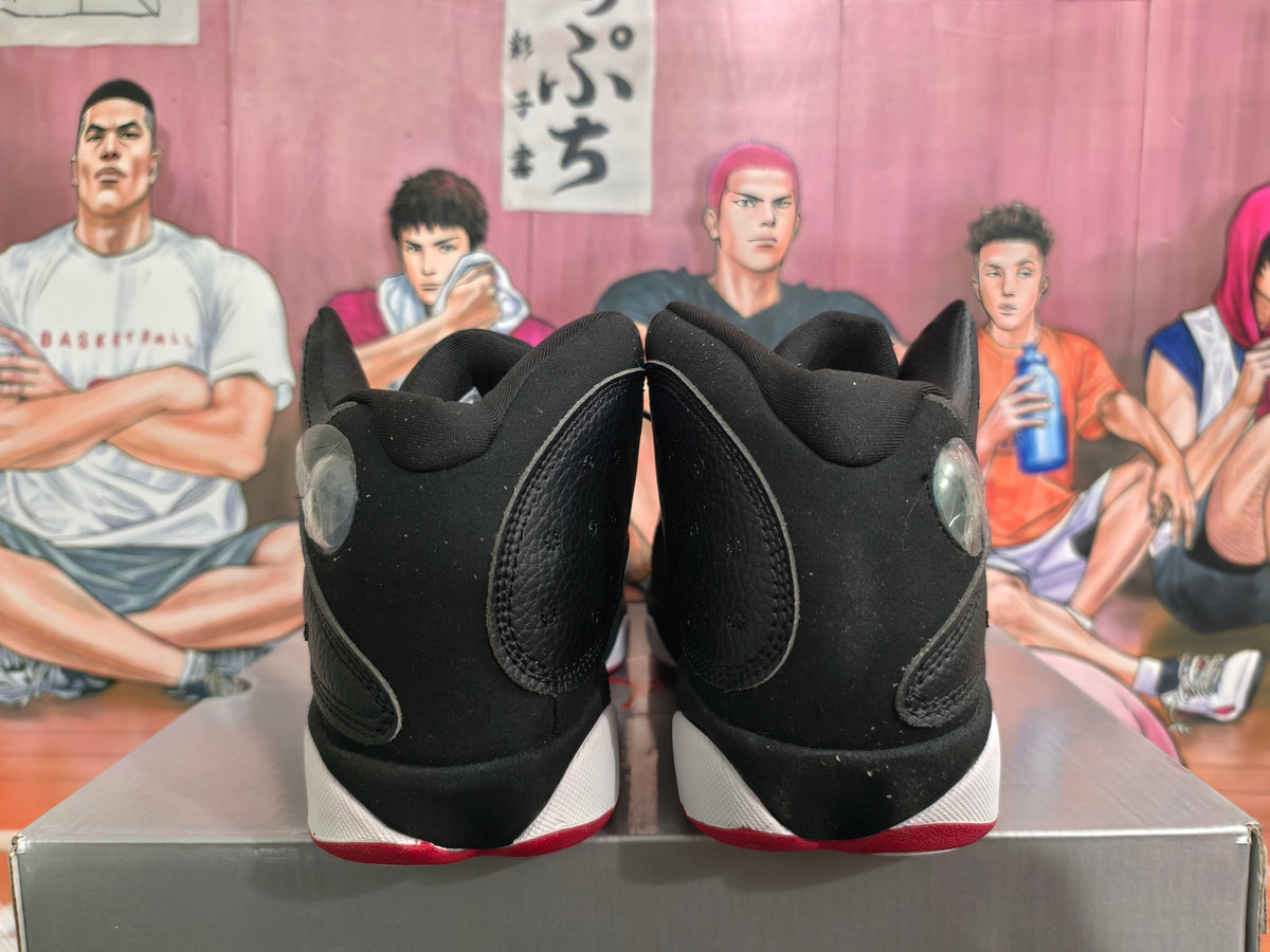 Rear view of black high-top basketball sneakers showing padded collars, heel details, white midsoles, and red outsole edges.