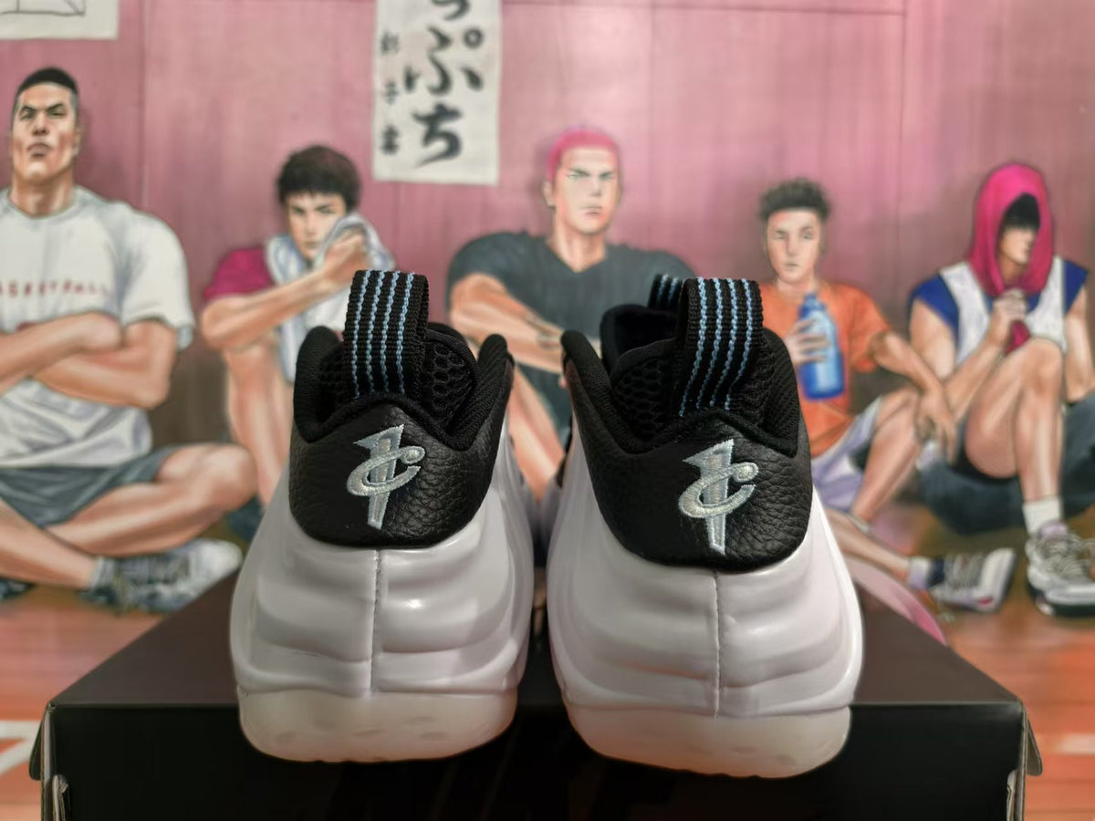 Rear view of white and black sneakers showing metallic silver heel branding and striped pull tabs.