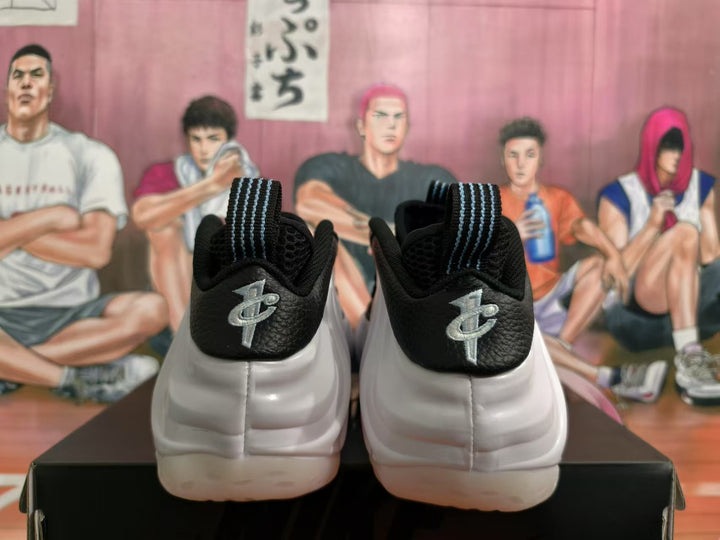 Rear view of white and black sneakers showing metallic silver heel branding and striped pull tabs.