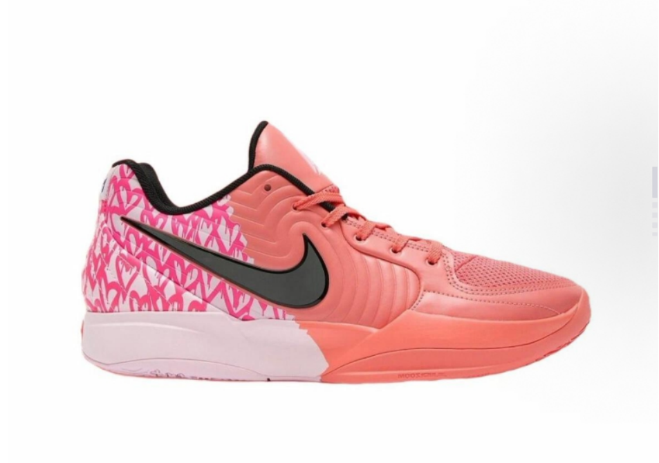 Side view of a pink Nike basketball sneaker with a black Swoosh, patterned heel panel, coral upper and contrasting sole.