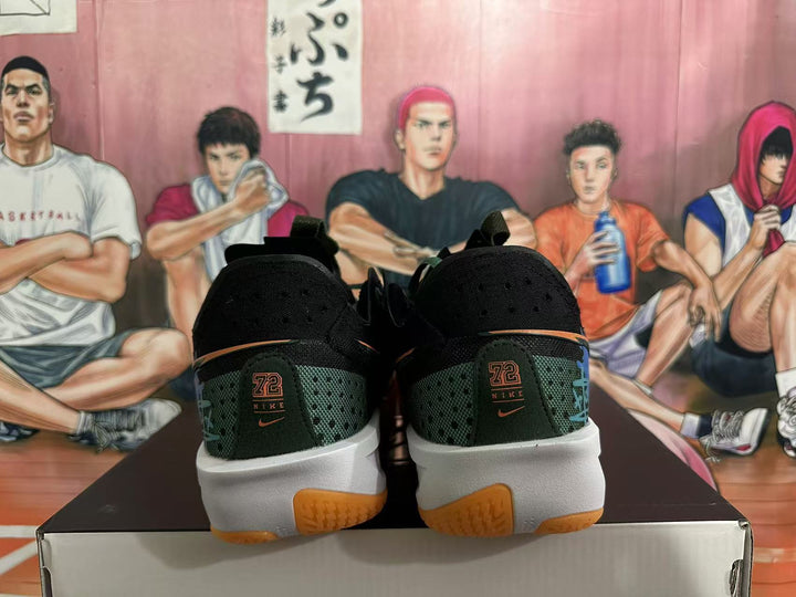 Rear view of black and dark green Nike basketball sneakers with orange accents, white midsoles, and gum-colored outsoles.