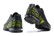 Rear and outsole views of black and volt Nike Air Max Plus sneakers.