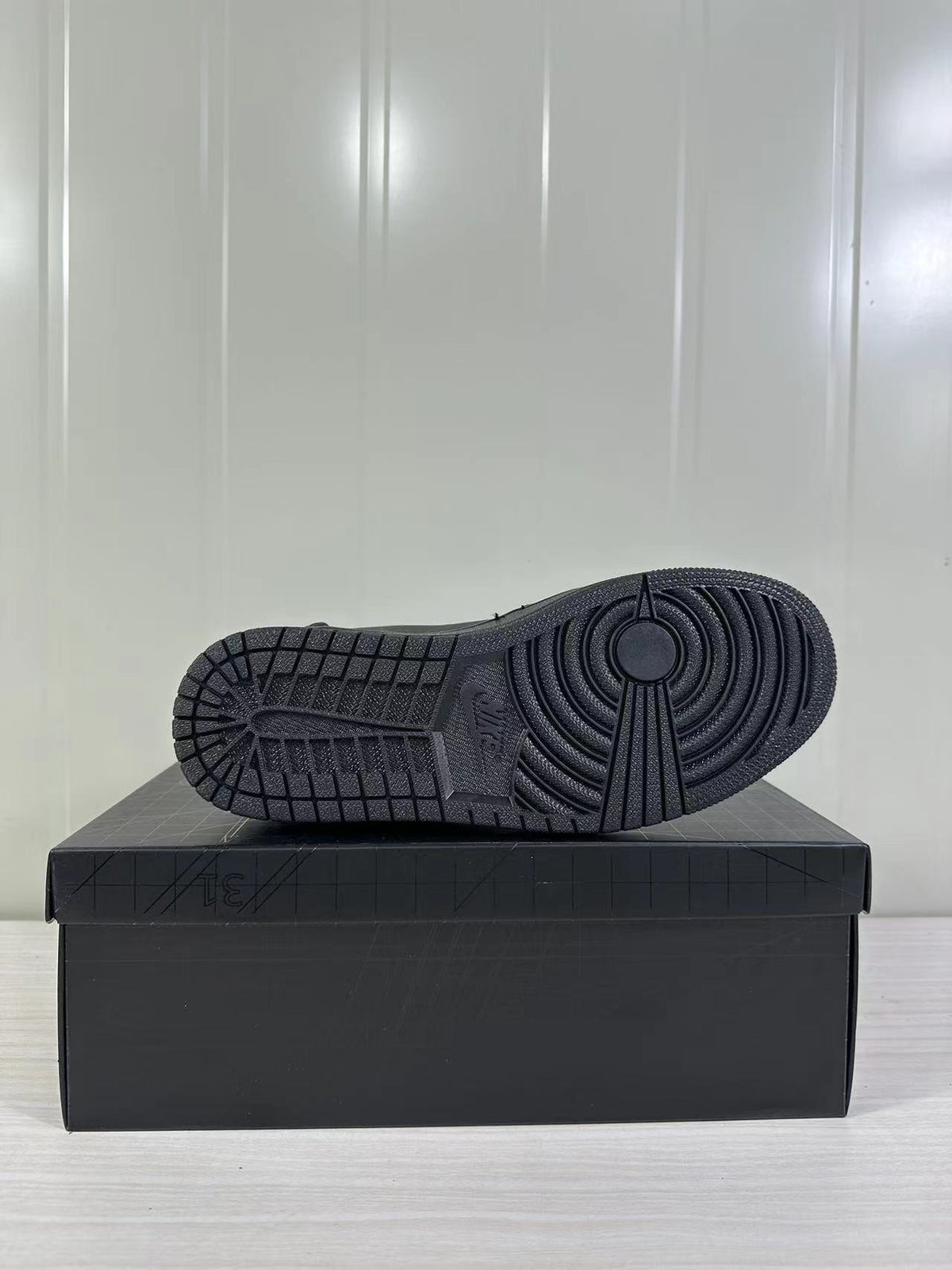 Black rubber outsole with circular traction pattern displayed on a black shoebox.