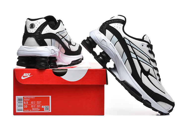 White and black Nike Shox R4 sneakers displayed with a red box; the box label shows sample size 8.5 US and 10 US Women.